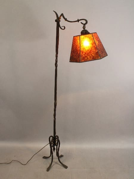 Antique 15638. Spanish Revival 1920's Wrought Iron Bridge Lamp with a twisted metal stand and a mica shade, illuminated in a room with a plain background.
