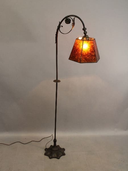 15640. Spanish Revival Bridge Lamps With Floral Motif with a curved metal stand and a single illuminated amber glass shade, set against a plain backdrop.