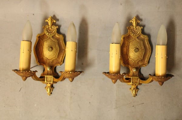 Two ornate gold wall sconces with candles.
