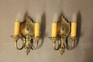 Two ornate wall sconces with candle lights.