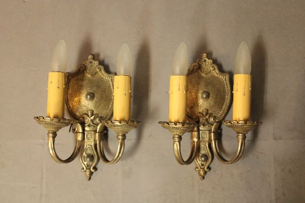 Two ornate wall sconces with candle lights.