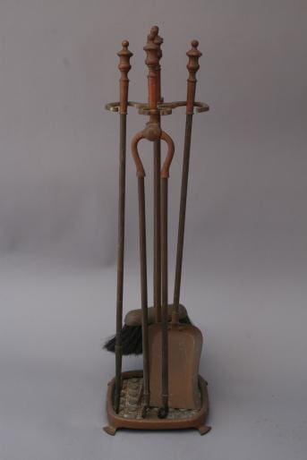 A set of 2415. Brass Fire Tool Set, including a broom, poker, and shovel, standing upright in a stand against a plain background.