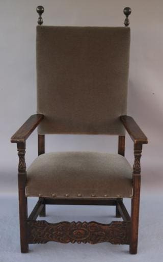 Tall upholstered wooden chair with armrests.