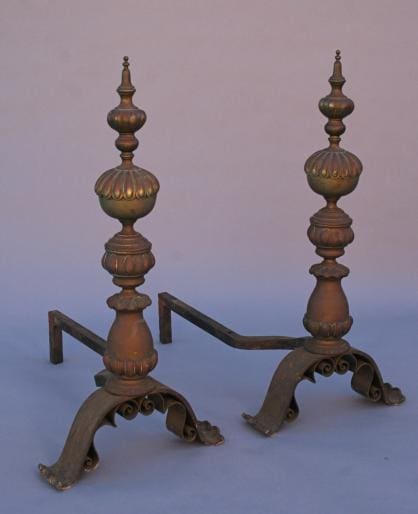 A pair of 5165. Spectacular Brass And Iron Andirons with ornate designs and curved feet on a plain background.