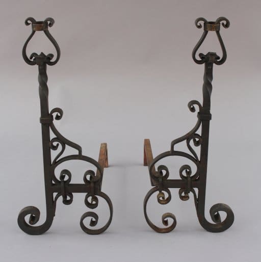 Two ornate Pair Of Wrought Iron Andirons with scroll designs on a light background.