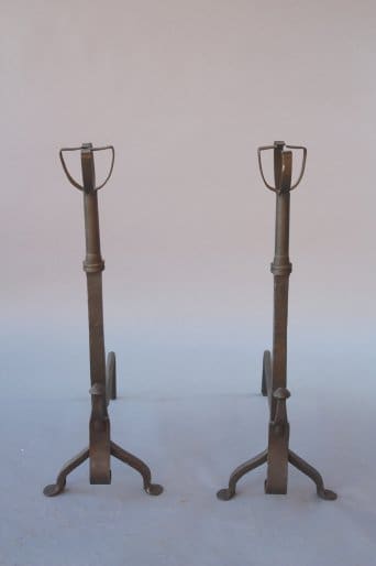 Two 7748. 1920's Pair Of Andirons with tripod bases and ring holders against a plain background.