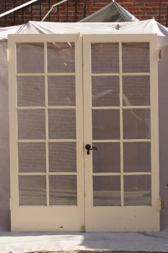 8287. Pair Of Spanish Revival Painted Double Doors with glass panes and a black handle, set in a brick building under a white canopy.