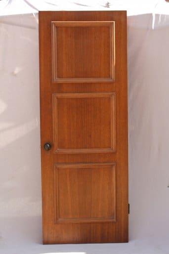 8290. 1920's Walnut Paneled Door with four panels and a round knob, standing isolated against a light fabric background.