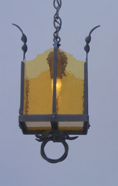 Hanging yellow lantern with decorative features.