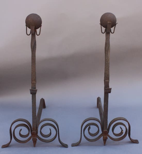 Two 1920's Pair of Spanish Revival Andirons with curled designs and spherical tops, standing on a neutral background.