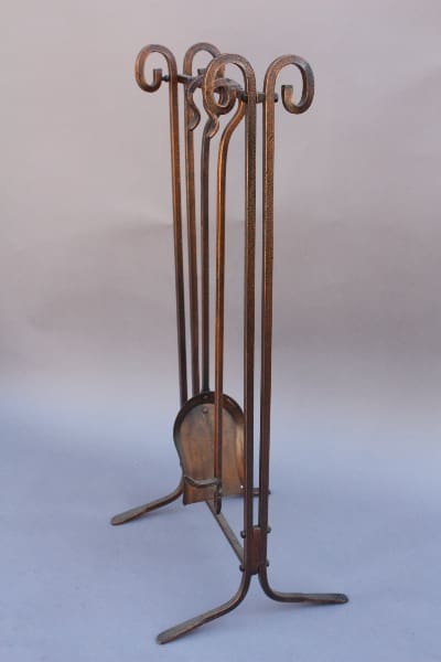 9550. Unique Copper Toned Fire Tool Set, consisting of a poker, shovel, broom, and stand, with decorative scrollwork, isolated on a light background.