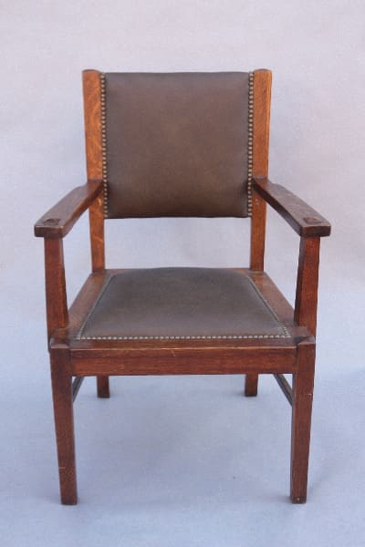 9801. 1910 Arts & Crafts Armchair with brown leather upholstery and brass tack accents, set against a neutral background.