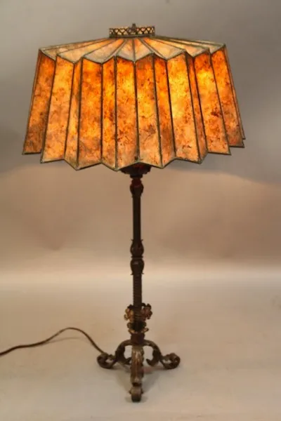 Antique 1920's Spanish Revival table lamp with a fantastic mica shade and ornate metal base, set against a neutral backdrop.