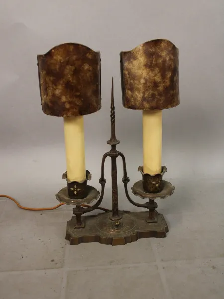 Antique double candlestick 15690. Pair of 1920's Spanish Revival Table Lamp with tarnished bronze base and two yellowed faux candles, each with a mottled brown lampshade, on a plain background.