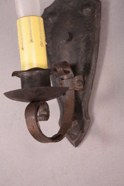 Vintage wrought iron wall sconce with yellow candle.