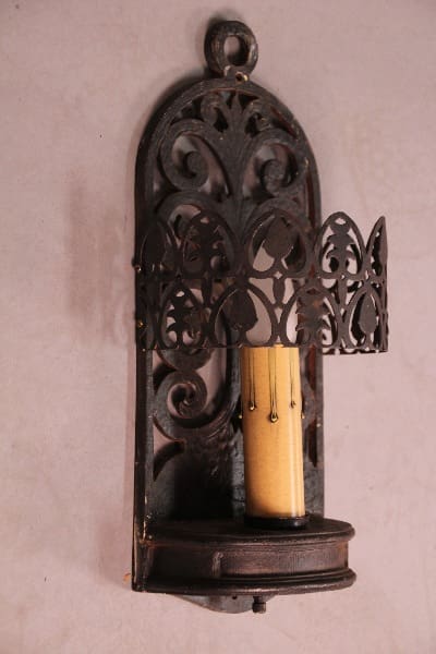 Ornate wall candle holder with lit candle.