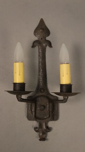 Wrought iron candle wall sconce with yellow bulbs.