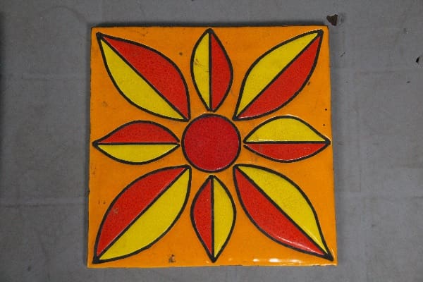 Orange tile with red and yellow flower design.
