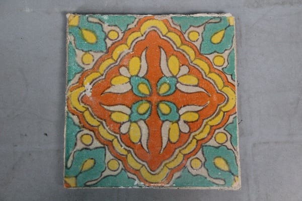 Ornate tile with yellow and orange floral pattern.