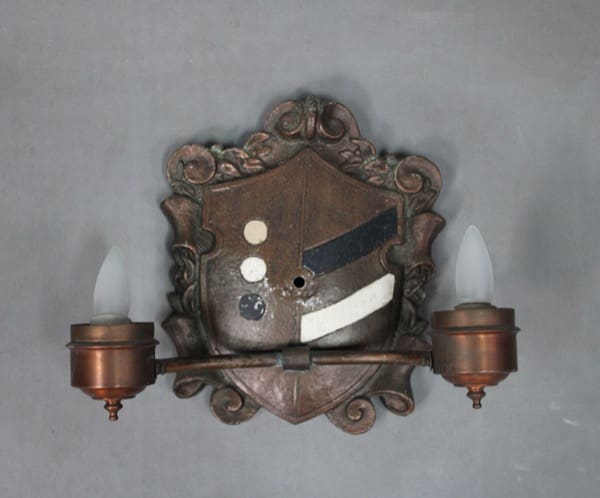 Wall-mounted antique sconce with shield design.