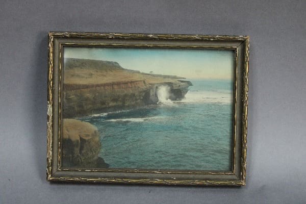 Framed coastal landscape with crashing waves.
