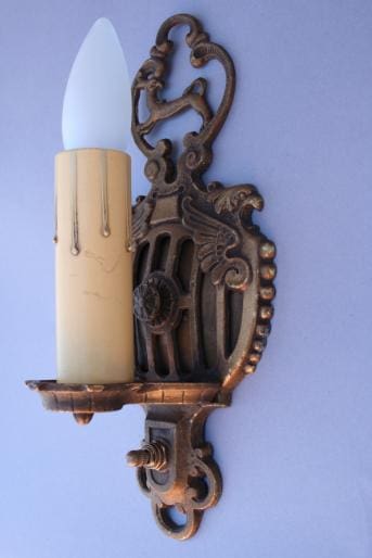 Ornate bronze wall sconce with candle bulb.
