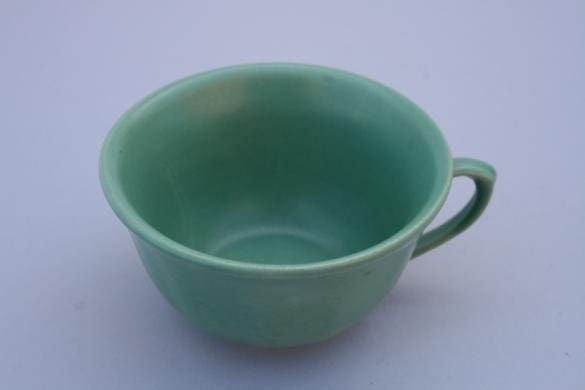Green ceramic teacup with handle.