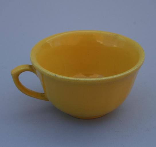 Yellow ceramic teacup with handle.