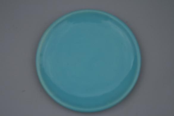 Turquoise circular plate on a gray background.