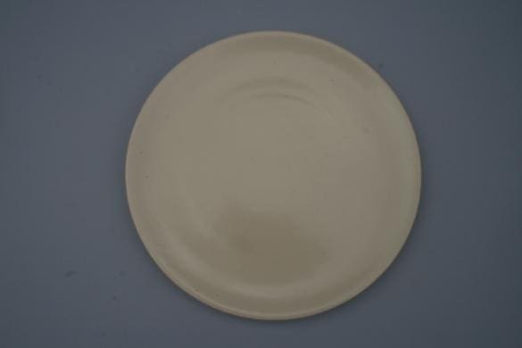 Plain round cream-colored plate on grey background.