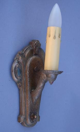 Bronze wall sconce with tapered light bulb.