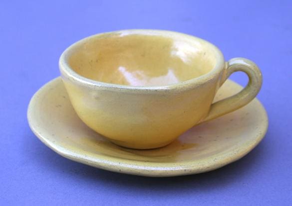 Yellow ceramic cup with matching saucer.