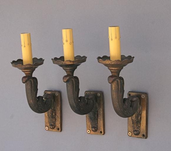 Three vintage wall sconces with candles.