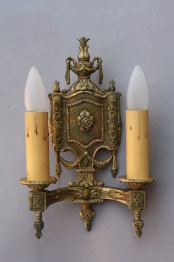 Vintage two-bulb wall sconce with ornate design.