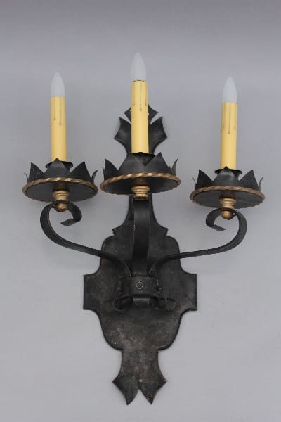 Three-candle black wall sconce with yellow candles.
