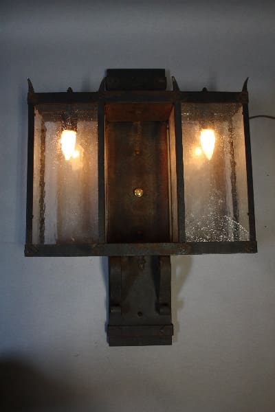 Rustic iron wall-mounted lantern with glass panels.