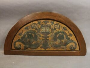 Semi-circular wooden panel with ornate design.