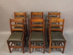 Six wooden chairs with green leather seats.