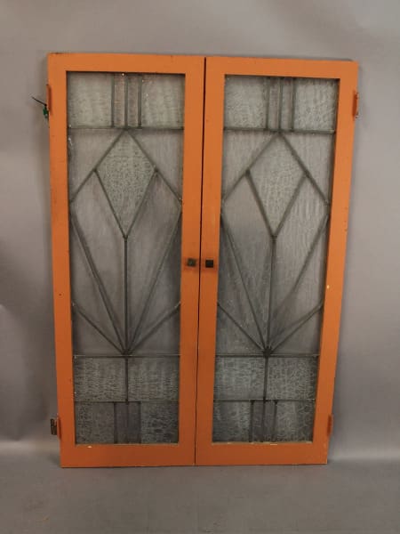 Orange-framed glass cabinet doors with geometric pattern.