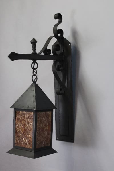 Wall-mounted wrought iron lantern with chain.