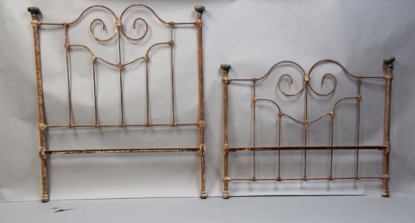 Two vintage metal headboards with decorative swirls.