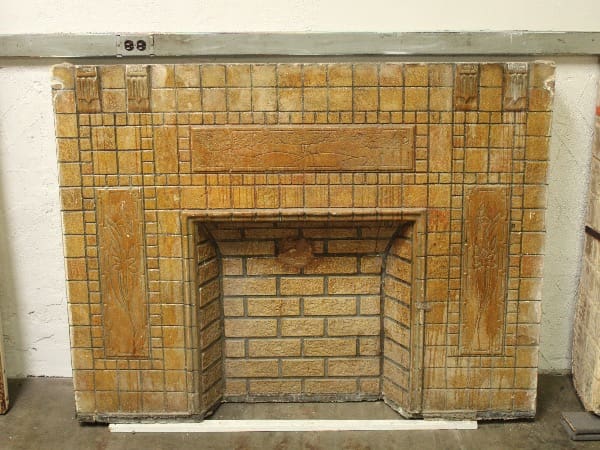 Vintage tiled fireplace against a white wall.