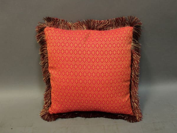 Red decorative pillow with patterned fringe.