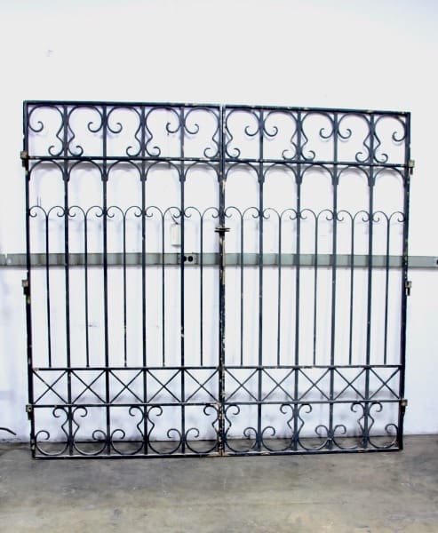 Ornate wrought iron gate against white wall.