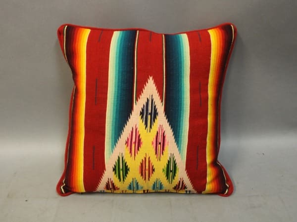 Colorful geometric patterned pillow on gray background.