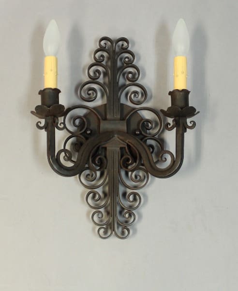 Ornate wrought iron wall sconce with candles.