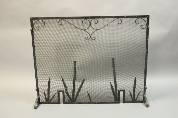 Decorative metal fireplace screen with mesh design.