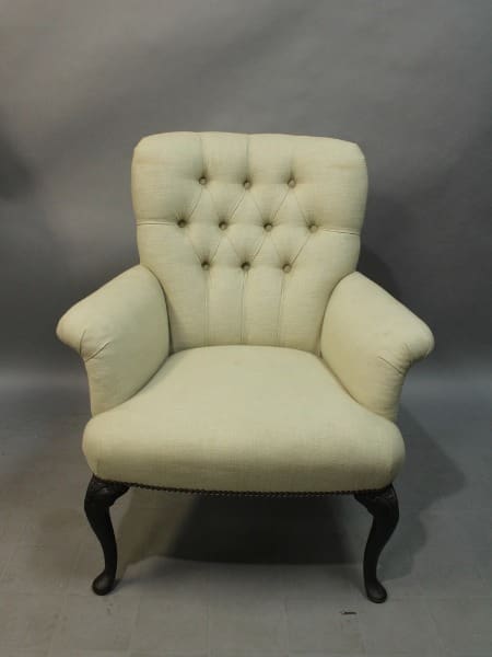 Cream tufted armchair with dark wooden legs.