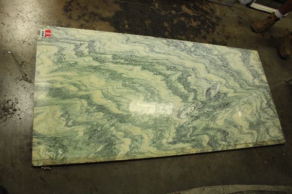 Green marble slab on concrete floor.