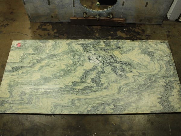 Green and white marble slab on floor.